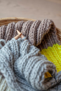 Knitting with fluffy wool and thick knitting needles in basket, earth tones Knitting with fluffy wool and thick knitting needles in basket, earth tones