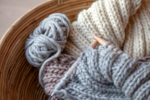 Knitting with fluffy wool and thick knitting needles in basket, earth tones Knitting with fluffy wool and thick knitting needles in basket, earth tones