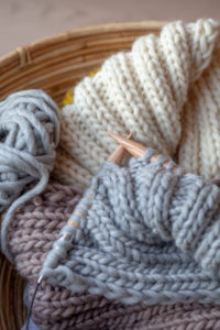 Knitting with fluffy wool and thick knitting needles in basket, earth tones Knitting with fluffy wool and thick knitting needles in basket, earth tones