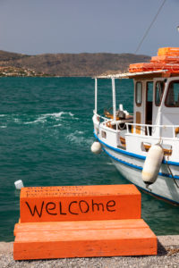 Boat in the port of Elounda. In front of it orange staircase with inscription "Welcome", Greece, Crete island, Kalydon Boat in the port of Elounda. In front of it orange staircase with inscription "Welcome", Greece, Crete island, Kalydon