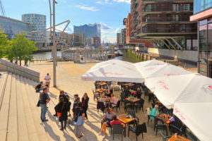 Magellan terraces with street cafe at the Sandtorhafen and Elbphilharmonie on the Elbe island Grasbrook in the Hafencity at the harbor, Hamburg, Hamburg State, Germany