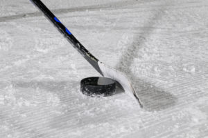 Ice hockey stick and puck on ice surface, close-up Ice hockey stick and puck on ice surface, close-up