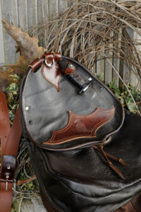 Falconer's bag with falconer's knife in front of decoration from dry branches Falconer's bag with falconer's knife in front of decoration from dry branches