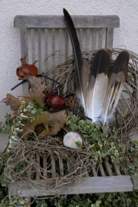 Eagle bonnets and eagle feathers arranged on wooden chair, still life Eagle bonnets and eagle feathers arranged on wooden chair, still life