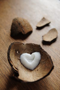 Piece of coconut peel with heart of coconut on dark wood, blurred peels in the background Piece of coconut peel with heart of coconut on dark wood, blurred peels in the background
