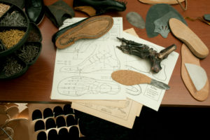 Shoemaker's workshop, drawing for tailor-made shoes, unfinished handcrafted shoe and soles Shoemaker's workshop, drawing for tailor-made shoes, unfinished handcrafted shoe and soles