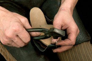 Shoemaker's workshop, shoemaker nailing leather into the wooden model Shoemaker's workshop, shoemaker nailing leather into the wooden model