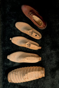 Handmade wooden models in shoemaker's workshop, work piece from rough to fine on black ground Handmade wooden models in shoemaker's workshop, work piece from rough to fine on black ground