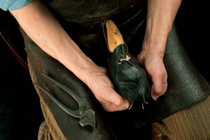 Shoemaker's workshop, shoemaker putting black leather over the wooden model Shoemaker's workshop, shoemaker putting black leather over the wooden model