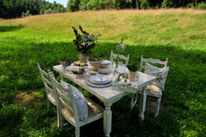laid white dining table on a summer meadow laid white dining table on a summer meadow