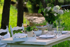 Covered white table with bunch of flowers on the brook, close up Covered white table with bunch of flowers on the brook, close up
