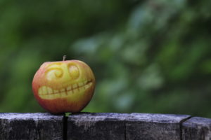 Apple with carved face in front of blurred background, close up Apple with carved face in front of blurred background, close up