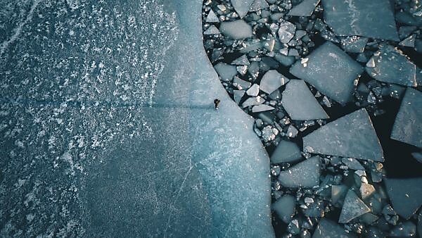 Ein einsamer Mensch auf einer Abbruchkante in der Ostsee an der Küste von Turku, Finnland. Die Eisschollen entstehen durch das passieren von Fähren und Schiffen Ein einsamer Mensch auf einer Abbruchkante in der Ostsee an der Küste von Turku, Finnland. Die Eisschollen entstehen durch das passieren von Fähren und Schiffen