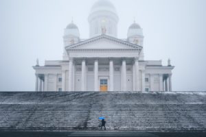 A woman with a blue umbrella in the fog / rain in front of the cathedral in Helsinki, Finland A woman with a blue umbrella in the fog / rain in front of the cathedral in Helsinki, Finland