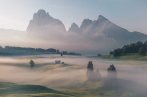 Sunrise over the Seiser Alm / Alpe di Siusi in the Dolomites, South Tyrol, Italy. Fog obscures the individual forest sections and alpine huts. Sunrise over the Seiser Alm / Alpe di Siusi in the Dolomites, South Tyrol, Italy. Fog obscures the individual forest sections and alpine huts.