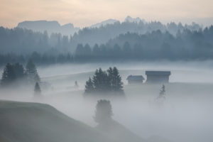 Sonnenaufgang über der Seiser Alm / Alpe di Siusi in den Dolomiten, Südtirol, Italien. Nebel verschleiert die einzelnen Waldabschnitte und Almhütten Sonnenaufgang über der Seiser Alm / Alpe di Siusi in den Dolomiten, Südtirol, Italien. Nebel verschleiert die einzelnen Waldabschnitte und Almhütten