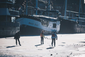 Drei Jungen spielen Eishockey auf dem zugefrorenen Fluss Aura in Turku, Finnland Drei Jungen spielen Eishockey auf dem zugefrorenen Fluss Aura in Turku, Finnland