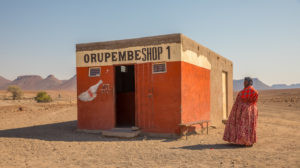 Woman in traditional Dutch clothes in front of a grocery store in the desert, Woman in traditional Dutch clothes in front of a grocery store in the desert,