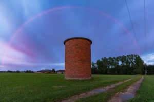 Rainbow during a sunset with a spectacularly colored sky. In the foreground a brick silo. Rainbow during a sunset with a spectacularly colored sky. In the foreground a brick silo.
