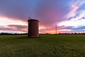 Sonnenuntergang bei Regen. Im Vordergrund ein Backsteinsilo, im Hintergrund ein spektakulär gefärbter Himmel Sonnenuntergang bei Regen. Im Vordergrund ein Backsteinsilo, im Hintergrund ein spektakulär gefärbter Himmel