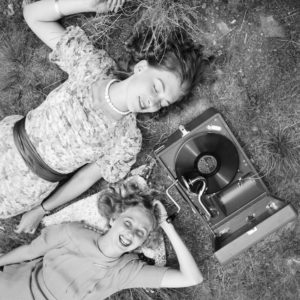 Two young women lying in a lawn and listening to the lastest hits from their Electrola gramophone, Germany 1930s. Two young women lying in a lawn and listening to the lastest hits from their Electrola gramophone, Germany 1930s.