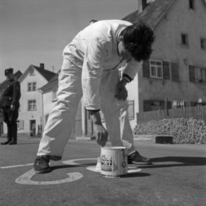 A painter marking parking areas on the street, Germany 1950s. A painter marking parking areas on the street, Germany 1950s.