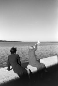 Two young women sitting on the terrace are waving at a sailing boat on the Chiemsee with a handkerchief Two young women sitting on the terrace are waving at a sailing boat on the Chiemsee with a handkerchief