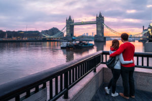 A couple stands arm in arm in London at Tower Bridge for sunrise. A couple stands arm in arm in London at Tower Bridge for sunrise.