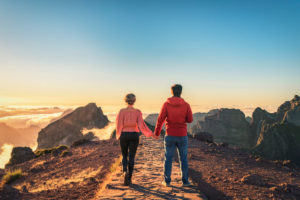 A couple walks hand in hand on Madeira over the mountain Pico do Arieiro. You can see the cloud cover at sunset. A couple walks hand in hand on Madeira over the mountain Pico do Arieiro. You can see the cloud cover at sunset.