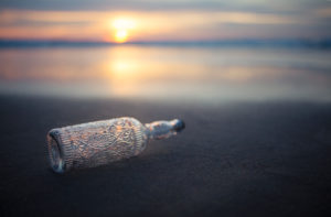 Glasflasche mit Verzierungen am Strand in abendlichem Licht Glasflasche mit Verzierungen am Strand in abendlichem Licht