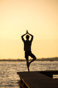 Young man doing yoga on a jetty by the lake Young man doing yoga on a jetty by the lake