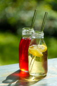Two small glass bottles with homemade lemon and elderberry lemonade on a garden table Two small glass bottles with homemade lemon and elderberry lemonade on a garden table