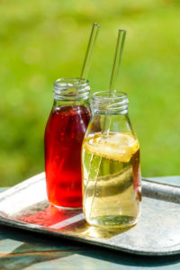 Two small glass bottles with homemade lemon and elderberry lemonade on a garden table Two small glass bottles with homemade lemon and elderberry lemonade on a garden table