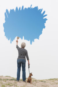 Senior woman with dog on lead painting blue sky in air Senior woman with dog on lead painting blue sky in air