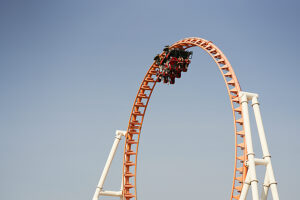 Roller coaster at the peak of a loop against a clear blue sky.