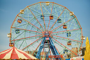 Vibrant Ferris wheel with colorful cabins against a sunny sky at an amusement park.