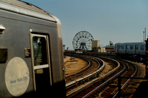 A New York City subway train with a view of a ferris wheel in the distance.