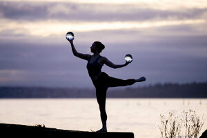 Silhouette of a person balancing with crystal balls by a serene waterside at sunset. WA, USA