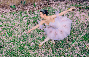 Ballet dancer in a tutu gracefully poses on a field of pink flowers. WA, USA