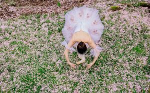 Ballerina in a delicate tutu gracefully poses amidst a field of pink blossoms. WA, USA