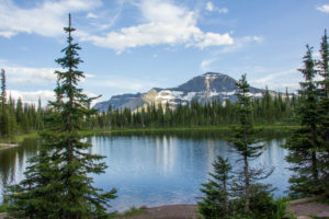 Mountain lake in the coniferous forest with mountain in the background, Rocky Mountains, Canada Mountain lake in the coniferous forest with mountain in the background, Rocky Mountains, Canada