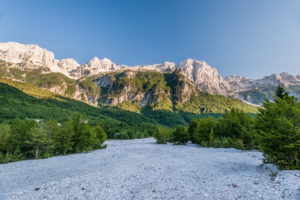 A dirt road leads through the dried out in summer river bed of the Valbona uphill towards Theth. Valbona (Valbonë), Kukës, Albania. A dirt road leads through the dried out in summer river bed of the Valbona uphill towards Theth. Valbona (Valbonë), Kukës, Albania.