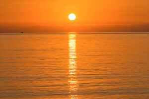 The sun sets in orange light over the Mediterranean near Sicily.