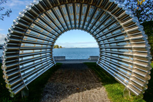 View of Lake Constance through a tunnel made of stainless steel pipes on a sunny fall day on the shore of Lake Constance. Bregenz, Vorarlberg, Austria.