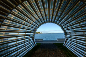 View of Lake Constance through a tunnel made of stainless steel pipes on a sunny fall day on the shore of Lake Constance. Bregenz, Vorarlberg, Austria.