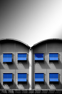 Modern corrugated iron facade of a residential house with rows of windows and blue awnings Modern corrugated iron facade of a residential house with rows of windows and blue awnings