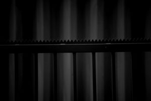 Side of a cargo container in the background, fence with sharp projections, close-up, detail Side of a cargo container in the background, fence with sharp projections, close-up, detail