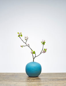 Blaue Vase mit Apfelzweig und Blüten auf Holztisch Blaue Vase mit Apfelzweig und Blüten auf Holztisch