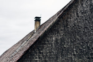 Dach mit Ziegeln und Kamin, alte Schindeln, grau und verwittert an einem Holzhaus im Schwarzwald Dach mit Ziegeln und Kamin, alte Schindeln, grau und verwittert an einem Holzhaus im Schwarzwald