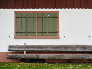 view to a house wall with a closed window and a wooden bench